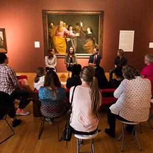 Dr. 亚历山大·里奇(Alexander Rich)和其他人聚集在一个画廊房间里，坐在一起讨论艺术品.